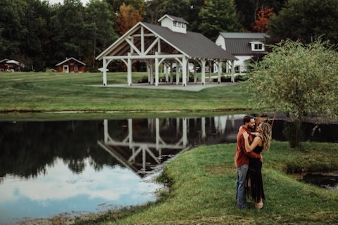 Wedding couple standing near pond at Morning Glory venue with pavilion in the background